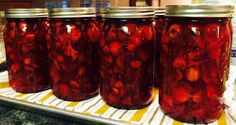 four jars filled with red pickles sitting on top of a counter next to each other