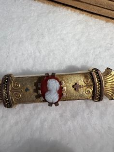 a gold bracelet with a red and white face on it