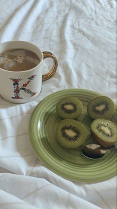 kiwi slices on a green plate next to a cup of coffee