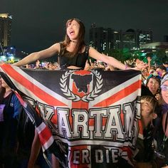 a woman holding up a flag in front of a crowd