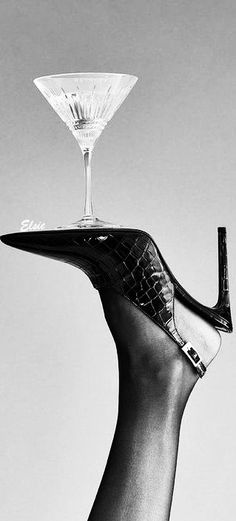 a woman's hand holding a wine glass on top of a shoe shaped tray