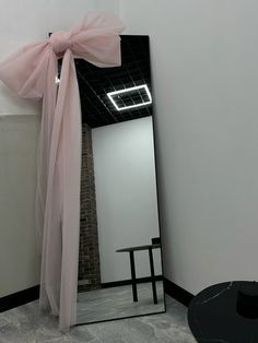 a mirror with a pink bow hanging from it's side next to a table