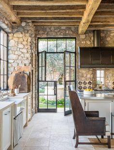 a kitchen with stone walls and flooring next to an open door that leads to a patio