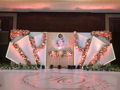 a stage set up for a wedding with flowers and an image on the wall behind it