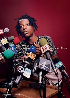 a man with dreadlocks sitting in front of microphones