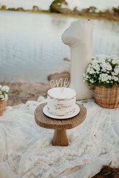 a white cake sitting on top of a wooden table next to a body of water