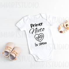 a baby bodysuit with the words primer nero en camino next to it