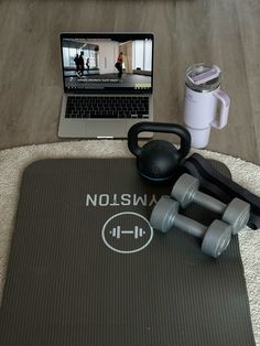 there is a gym mat with dumbs and a laptop on it