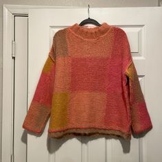 an orange and pink sweater hanging on a door