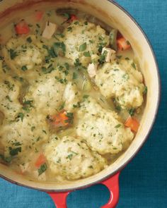 a pot filled with chicken and dumplings on top of a blue table cloth next to a spoon