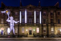 a large building with a lit up statue on it's side