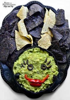 a black plate topped with chips and guacamole