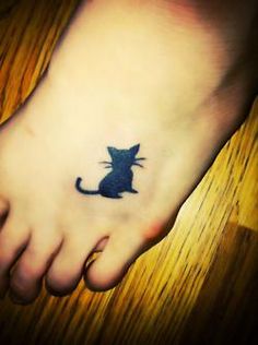 a small black cat tattoo on the foot