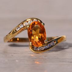 The Fire: Citrine And Natural Diamond Bypass Ring In Yellow Gold. Embrace Elegance With Our Stunning Ring Featuring An Elongated Oval Brilliant-Cut Citrine As Its Centerpiece. The Bypass-Style Shank, Set With Round Brilliant-Cut Natural Diamonds To The North And South, Adds A Touch Of Sophistication. With A Total Diamond Weight Of Approximately 0.10 Carats, This Ring Is Crafted In 14 Karat Yellow Gold. Currently Sized At A Finger Size 6, Adjustments For A Personalized Fit Are Available Upon Request For An Additional Charge. Elevate Your Style With This Timeless Piece. Citrine Engagement Ring Vintage, Elongated Oval, Bypass Ring, North And South, The Fire, Womens Jewelry Rings, Round Brilliant, Timeless Pieces, Citrine