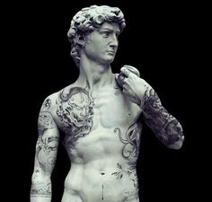 a statue of a man with tattoos on his arms and chest holding something in his hand