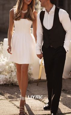 a man in a tuxedo is holding the hand of a woman wearing a white dress