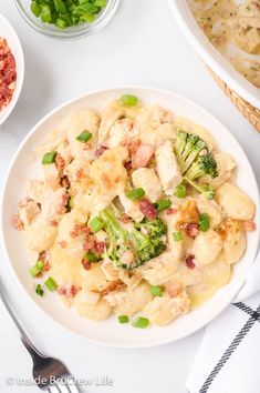 a white plate topped with pasta and broccoli next to bowls of meat and vegetables