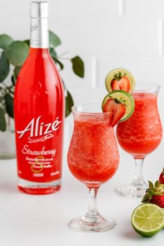 two wine glasses filled with strawberry margaritas next to a bottle of alze sparkling