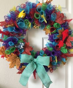 a colorful wreath is hanging on the front door with a bird and leaves decoration around it