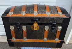 an old trunk is sitting outside on the ground next to a door with a towel under it