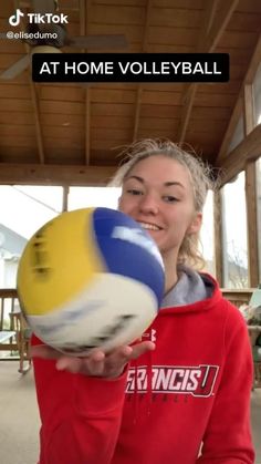 a girl in a red hoodie holding up a volleyball