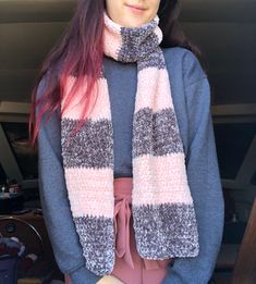 a woman with pink hair wearing a gray and white striped scarf over her shoulders, standing in front of a car