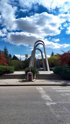 a large monument sitting on the side of a road under a blue sky with clouds