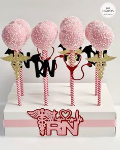 pink and gold cake pops are on top of a white box