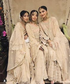 three women in white dresses sitting on a swing