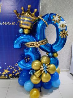 blue and gold balloons are arranged in the shape of an o, with a crown on top