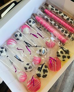 a box filled with cake pops covered in pink and white frosting next to each other