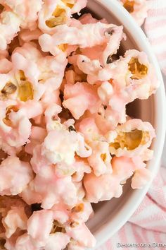 a white bowl filled with pink popcorn on top of a pink and white checkered table cloth