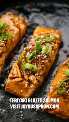 salmon with sesame seeds and scallions served on a black platter, ready to be eaten