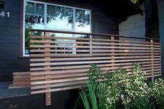 a wooden fence is in front of a black house with plants and trees around it