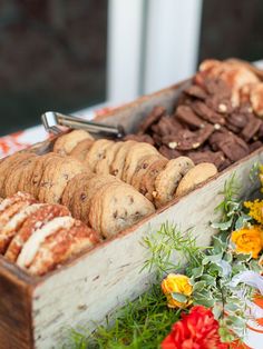 a wooden box filled with lots of different types of cookies and pastries on top of a table