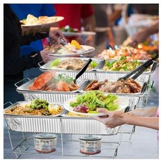 several trays of food being served to people