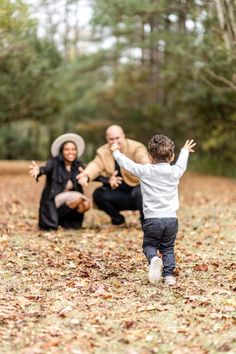 an adult and child playing in the leaves with their mother, dad and father's hands