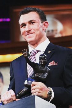 a man in a suit and tie holding a trophy