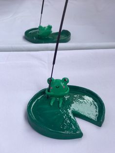 two green frog figurines sitting on top of a white table