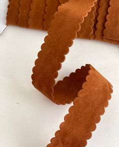 a roll of brown paper with scalloped edges on a white surface next to a pair of scissors