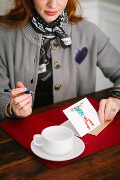 a woman sitting at a table with a cup and saucer