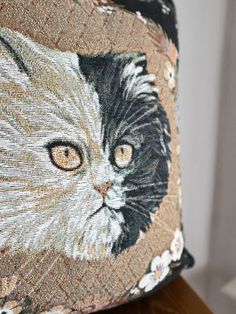 a close up of a pillow with a cat on it's face and eyes