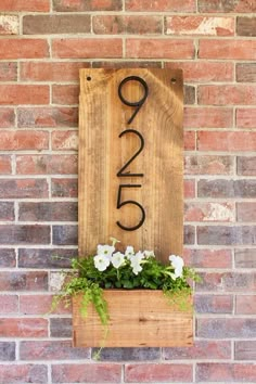 a wooden sign with the number twenty five on it and flowers growing out of it