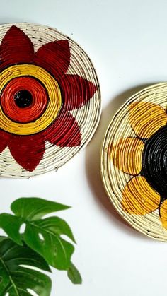 two baskets with flowers painted on them next to a plant