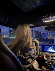 a blonde woman driving a car in the city at night