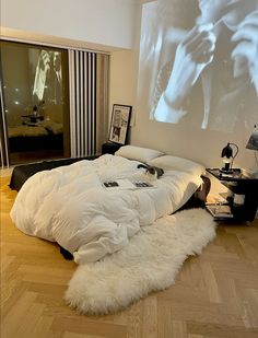 a large white bed sitting on top of a hard wood floor next to a projector screen