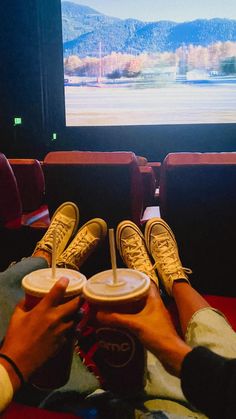 two people sitting in front of a flat screen tv with their feet on the seats