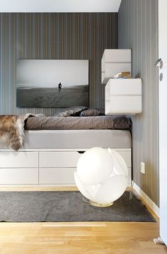 a cat is sitting on the edge of a bed in a room with striped walls