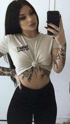 a woman with tattoos on her stomach taking a selfie