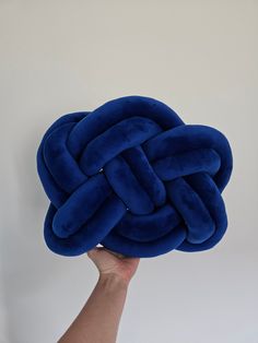 a hand holding up a blue knot cushion